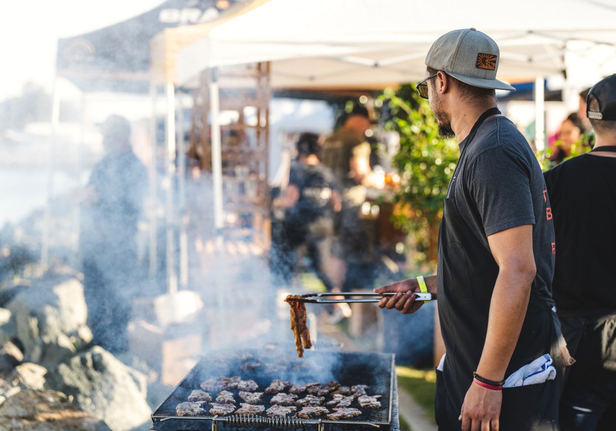 A chef grills Brandt Beef over a smoking grill on the waterfront