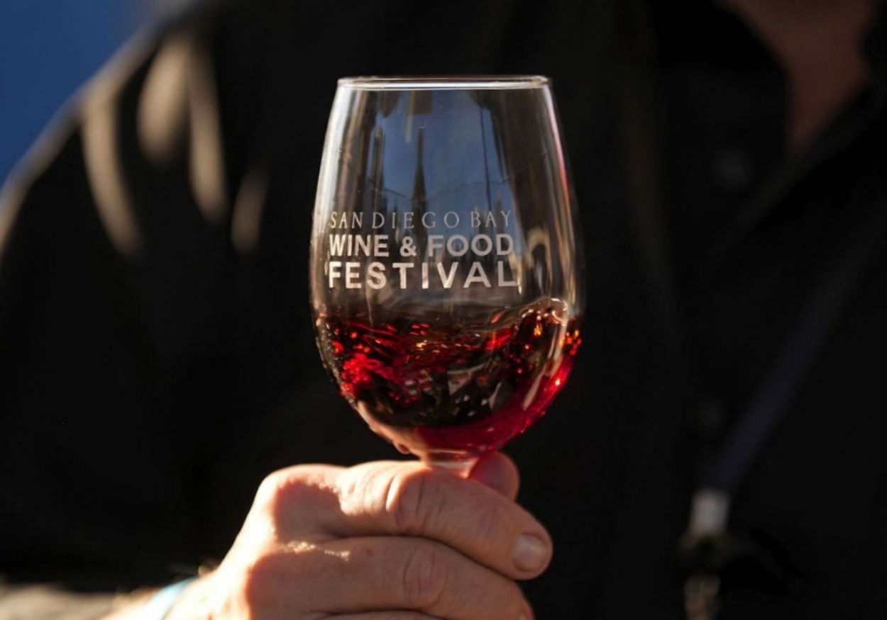 A glass of red wine raised in golden afternoon light