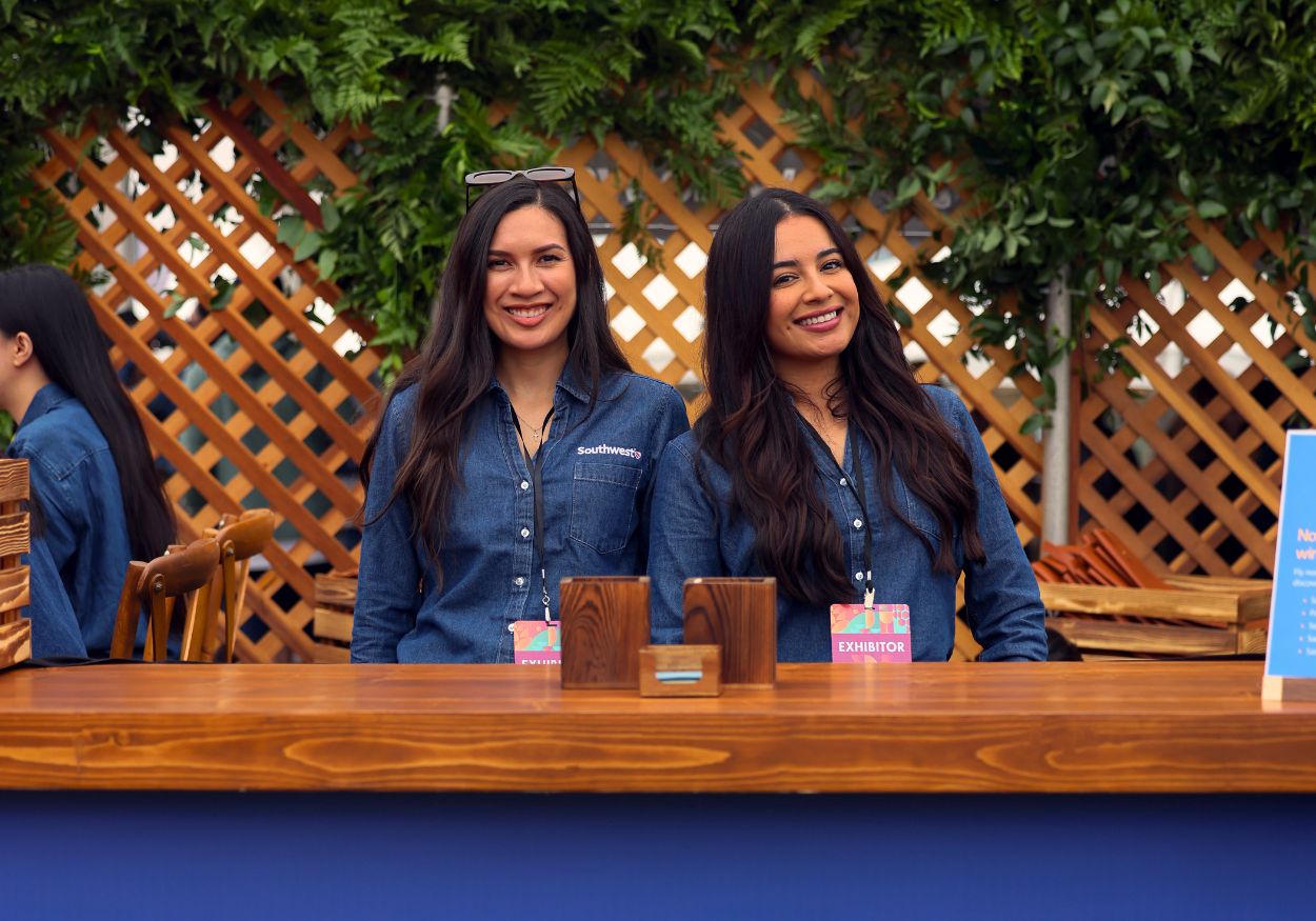 Two hosts stand behind the Southwest Airlines Sip & Ship Speakeasy bar