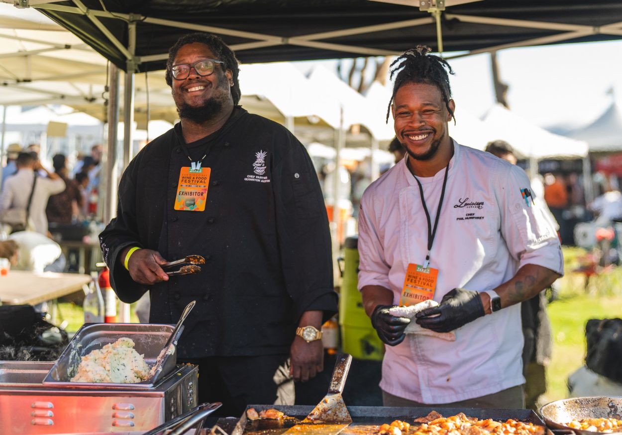 Two smiling chefs serve food at the Tropic Like It's Hot booth