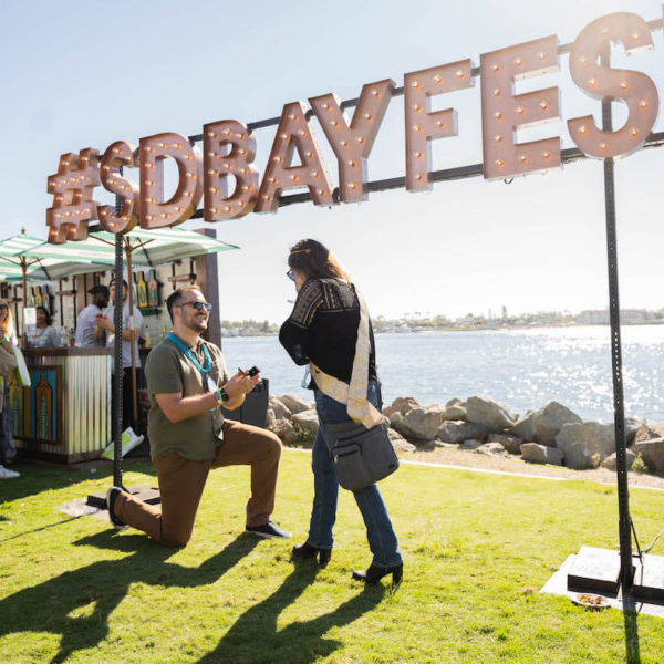 Man proposes to woman in front of San Diego Bay at San Diego Bay Wine & Food Festival Grand Tasting