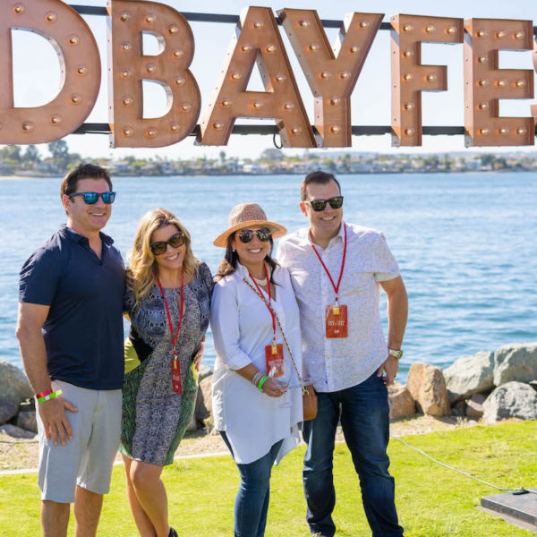Attendees posing for a photo in front of the San Diego Bay at the San Diego Bay Wine & Food Festival Grand Tasting